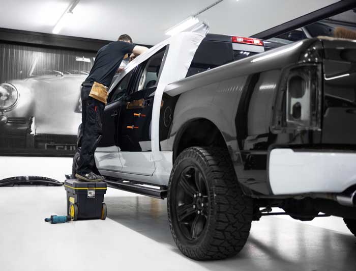 Technician repairing and repainting a pickup truck inside professional collision repair facility, showcasing expert Auto Body Shop Miami services for high-quality vehicle body repair and restoration
